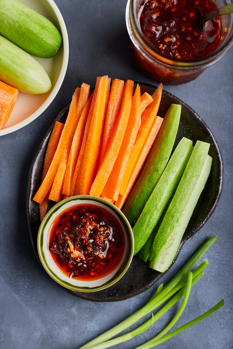 Small dish of chili oil and sliced carrot, cucumber for side dish